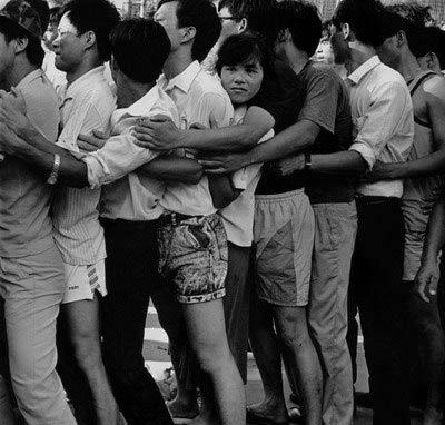 1992年深圳特区新股认购，抢购股民证的长队秩序极度混乱，众男女只好前胸贴后背，一个紧抱一个，在利益面前放弃了人与人之间的距离和尊严。